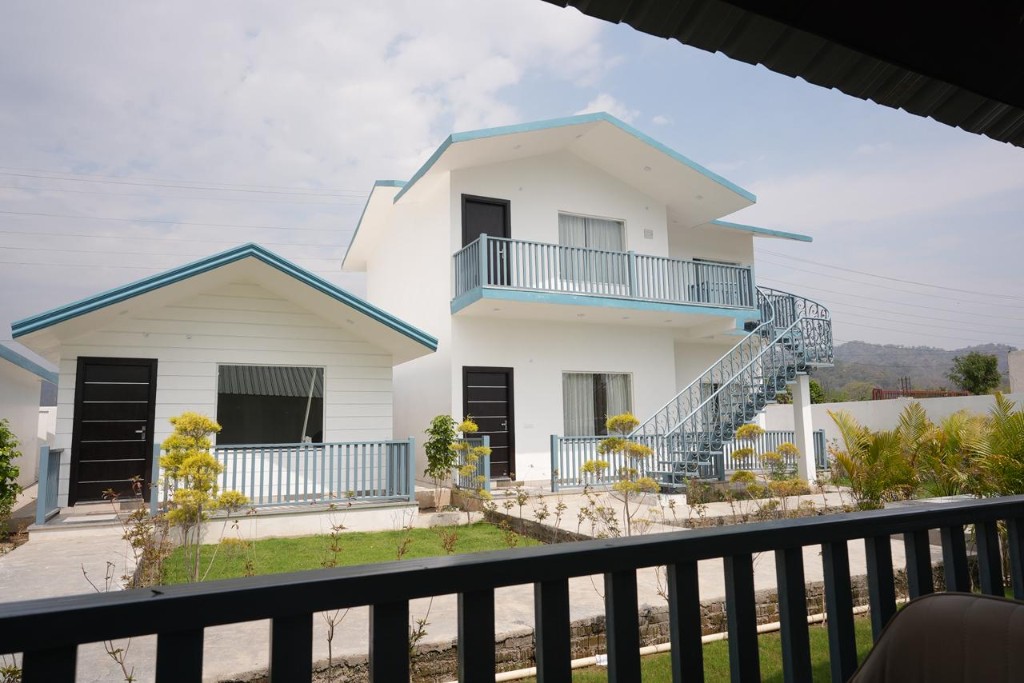 Two-storey white villa with external blue staircase and balcony